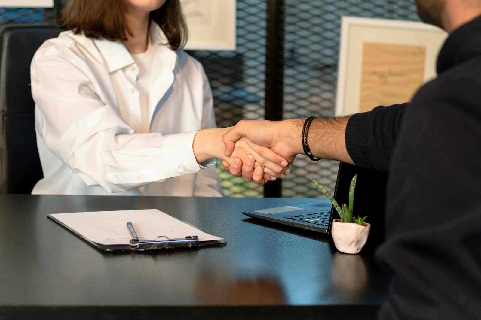 Handschlag zweier Geschäftspartner über Vertragsunterlagen